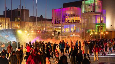 Kuvassa näkyy luistelijoita Tapiolan Jääpuutarhassa. Taustalla näkyy valaistu Espoon kulttuurikeskus.