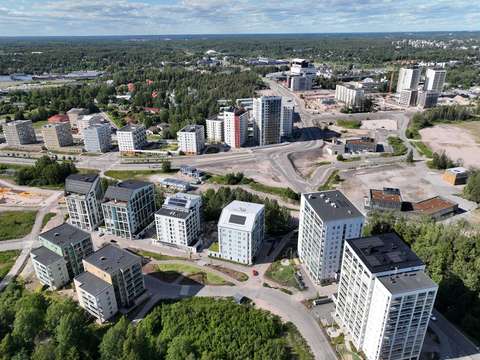 Flygbild med flervåningshus, vägar och träd.