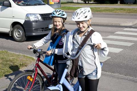 Två barn leder sina cyklar. De har precis korsat övergångsstället på ett säkert sätt.