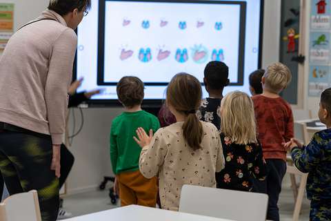 En grupp barn kollar tillsammans på bilder på en stor skärm.