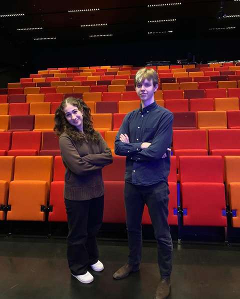 Kaksi nuorta katsovat kameraan kädet puuskassa.