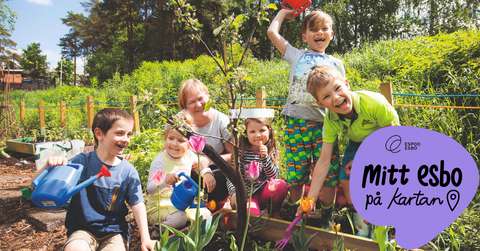 Fem barn står tillsammans med en vuxen på en grönskande odlingslott med trädgårdsredskap.