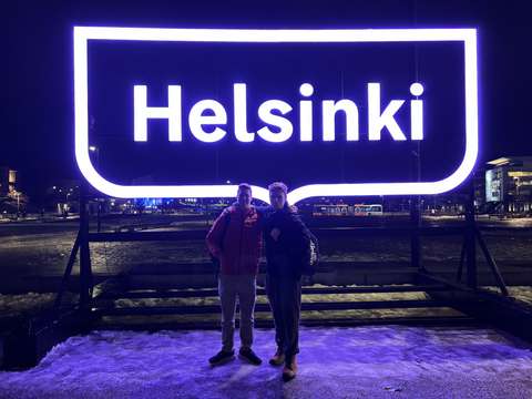kaksi opiskelijaa Helsinki-kyltin edessä pimeässä.