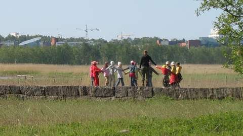 Lapsia ja aikuinen piirissä Laajalahden rannan kivilaiturilla.