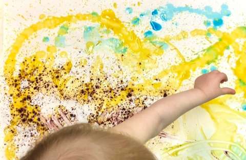 Vauva maalaa elintarvikepohjaisin värein keltaisella.