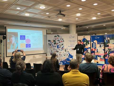 Mies pitää esitystä yleisön edessä.