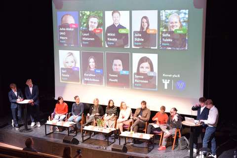 Vaalipaneelin keskustelijat istuvat vierekkäin auditorion lavalla.