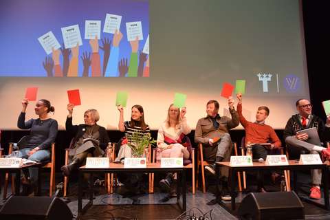 Vaalipaneelin keskustelijat istuvat vierekkäin auditorion lavalla.