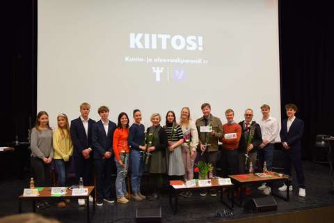 Vaalipaneelin keskustelijat seisovat vierekkäin auditorion lavalla.