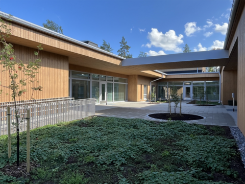 Rakennuksen sisäpiha, jossa laatoitusta, istutettuja puita sekä muuta kasvillisuutta.