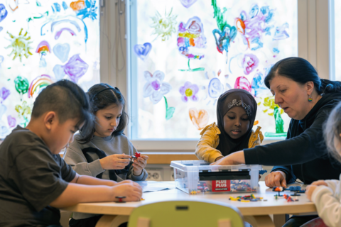 Lapsia ja opettaja pöydän ääressä rakentamassa plus plus -paloilla.