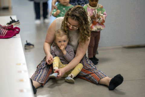 The employee helps the child put on the slippers.