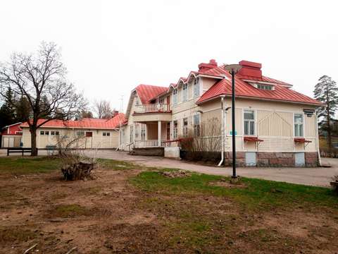 Vaalea vanha puurakennus, jossa on punainen katto.