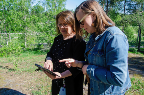 Huoltaja ja varhaiskasvatuksen työntekijä tutkivat eVaka-järjestelmää puhelimella.