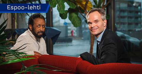 Ahmed Jama och Kai Mykkänen sitter i soffan och ser leende över soffryggen mot kameran.