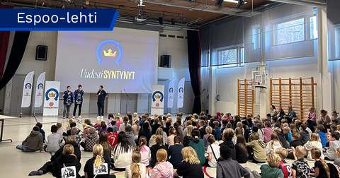 Koulaiset istuvat liikuntasalin lattialla ja kuuntelevat edessä puhuvia Kiekko-Espoon pelaajia.