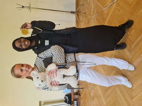 tytöt poseeraavat nallen ja mitalin kanssa