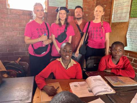 Opiskelijat kummipojan kanssa koulussa.