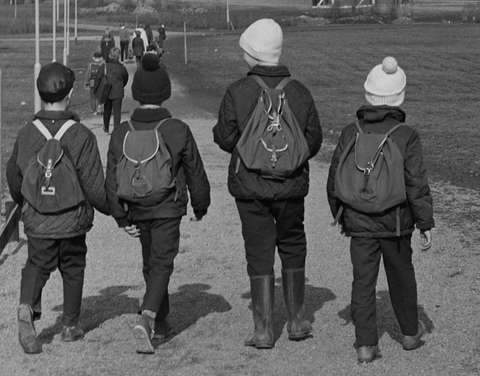 Fyra barn på vägen till skolan med ryggsäckar på ryggen.