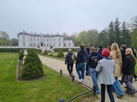 ryhmä opiskelijoita kävelee puistossa kohti vanhaa linnaa jossa meripihkamuseo.
