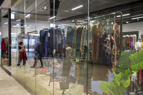 Lasiseinän takan myymälässä on paljon vaatteita.