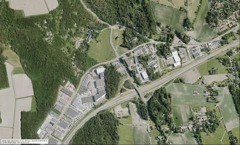 An aerial photograph that shows buildings on both sides of a road with lots of forests and fields.