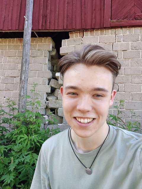 Julius Alanen utomhus framför en tegelvägg.