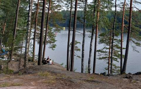 Valokuvassa on pilvinen kesäpäivä. Järven rannalla kalliolla on leiriytymispaikka.