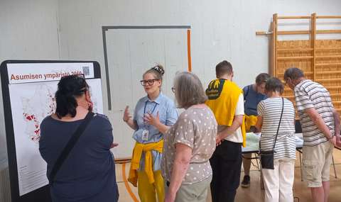 Asukkaat juttelevat kaavoittajien kanssa kartan edessä.