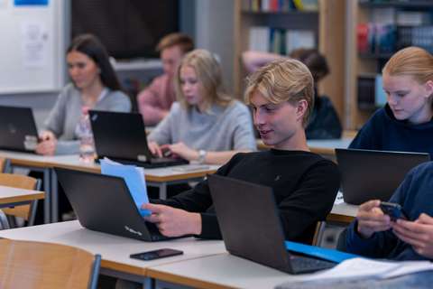 Studenter sitter i ett klassrum framför sina bärbara datorer.