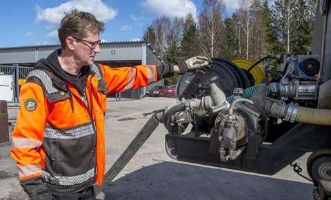 Photograph of a man in work clothes examining a work machine at a depot.