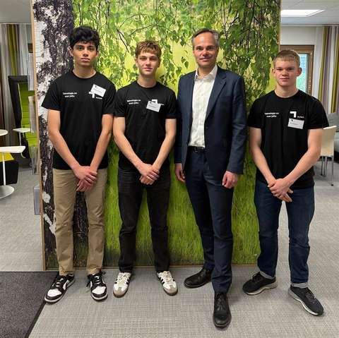 Kolme nuorta ja yksi aikuinen seisovat rinnakkain toimistotilassa.