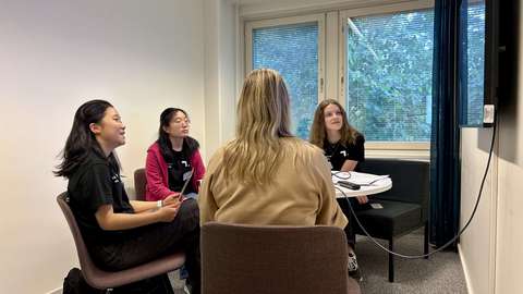 Neljä henkeä istuu pöydän ympärillä kokoushuoneessa.