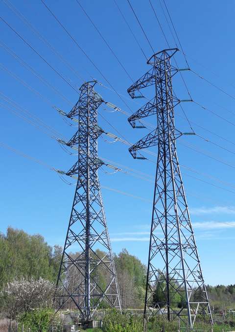 A photo of a summer landscape with two power line poles.