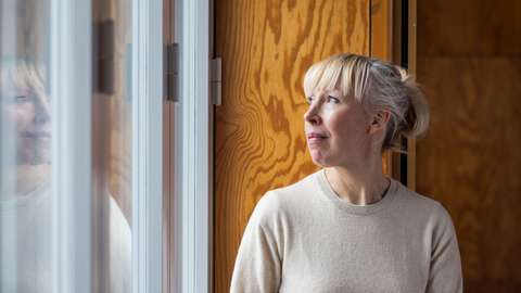 Saana Wang tittar ut genom fönstret och hennes spegelbild reflekteras tillbaka.