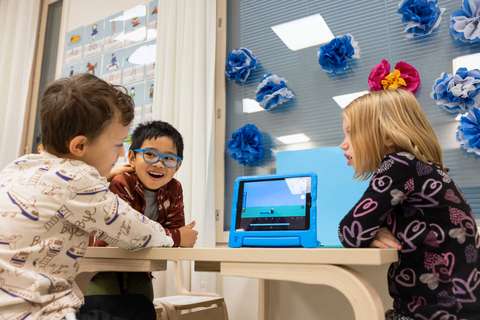 Kolme esikouluikäistä lasta pöydän ääressä.