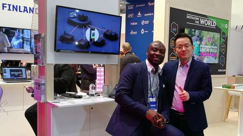 Two men pose for the camera. Several display boards in the background.