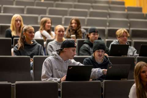 Studerande sitter i auditoriet med sina bärbara datorer framför sig.
