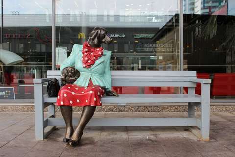 Espoon Nelli -taideteos istumassa Tapiola-penkillä Sellon kirjaston edustalla.