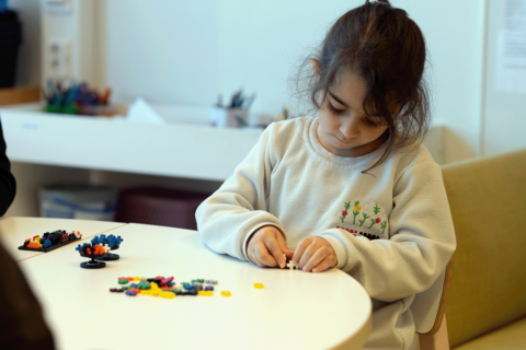 Ett barn bygger med Plus-Plus-bitar.