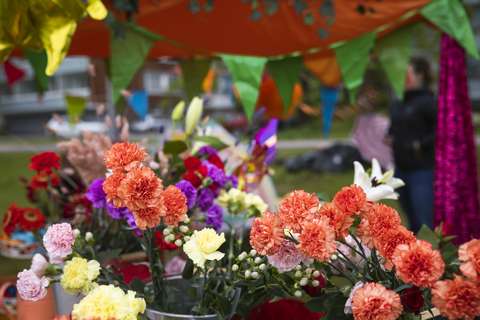 Blommor i krukor framför ett evenemangstält dekorerat med vimplar.