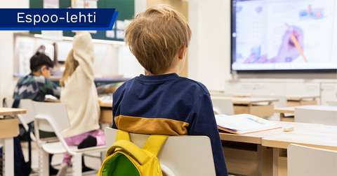 Koululaisia luokkahuoneessa selin kameraan.