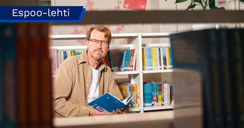 Timo Turtiainen pitää kirjaa käsissään ja katsoo kohti kameraa.