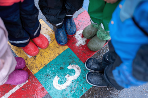 Lapsia jaloissaan värikkäitä kumisaappaita.