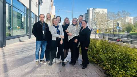 Ryhmä ihmisiä seisoo jalkakäytävällä, taustalla kaupunkinäkymä Espoosta.