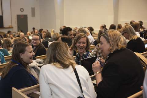 People sitting in a lecture hall are laughing.