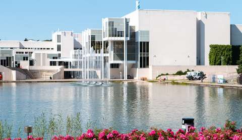 Kuvassa etualalla vettä ja kasveja ja takana kulttuurikeskuksen rakennus.