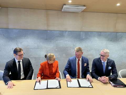 Ihmisiä allekirjoittamassa sopimusta pöydän ääressä.