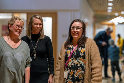 Tre anställda inom småbarnspedagogik står i daghemmets korridor och ler.