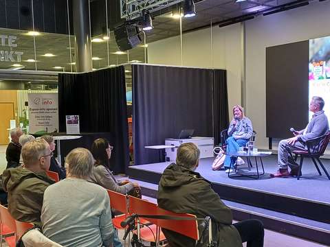 Karin Collins och intervjuaren Larson Österberg på scen i Sellos bibliotek. Publiken sitter i förgrunden.